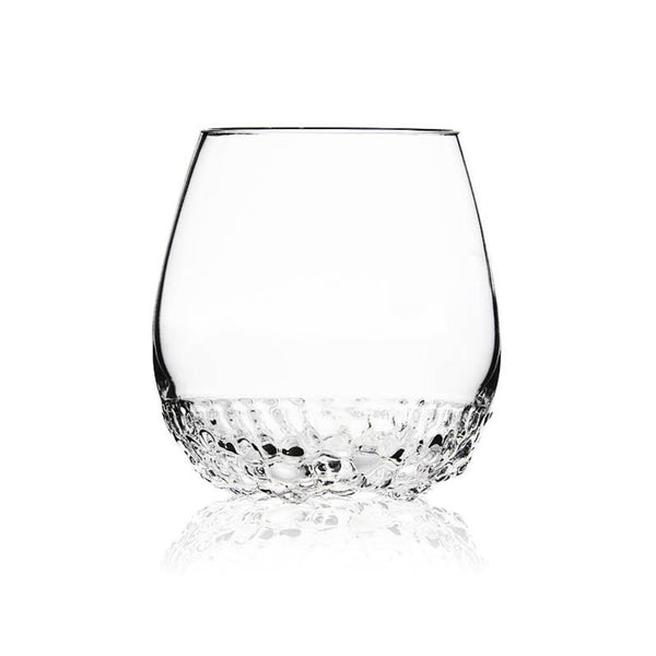 A clear glass rocks tumbler with a textured, faceted hammered base, shown on a clean white background with a soft reflection below.