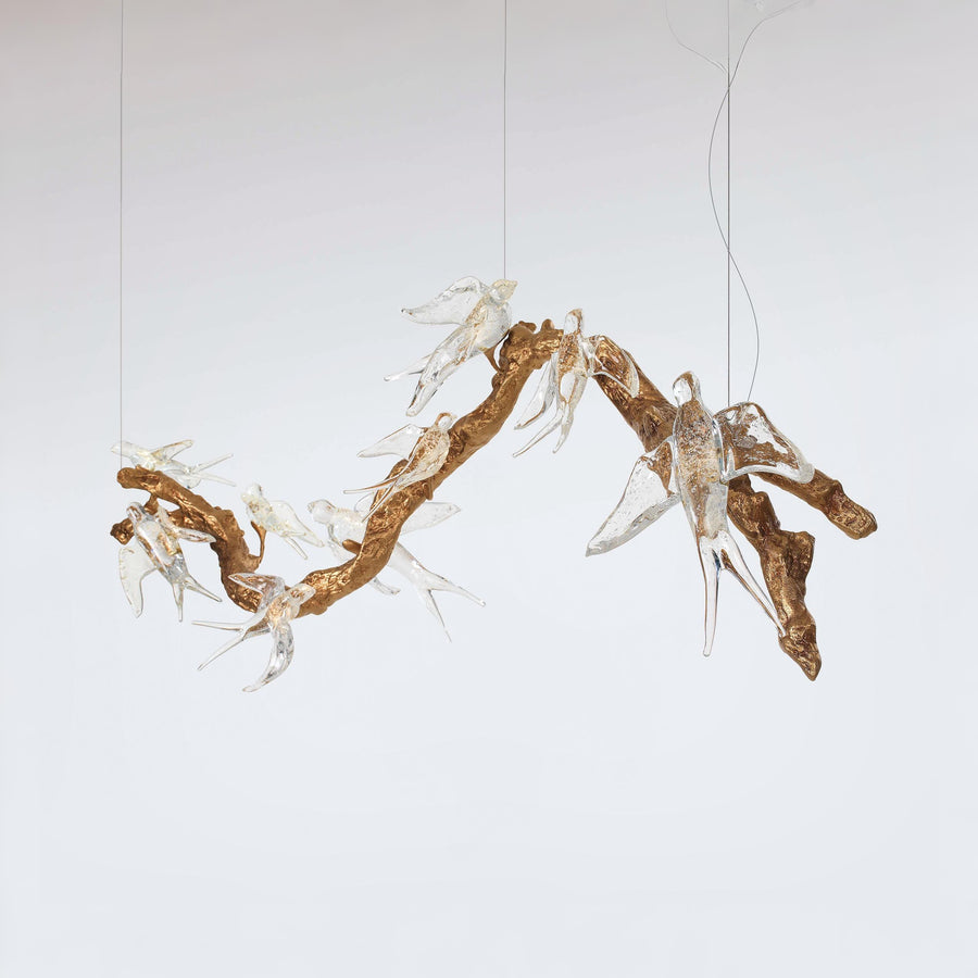 A chandelier with artistic arrangement of branches and white voa birds on a plain background