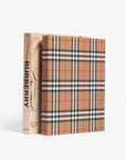 Hardcover and slip case in linen. Burberry coffee table book by Assouline, celebrating 165 years of British style, iconic trench coats, and timeless luxury through stunning illustrations and stories.