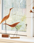 A pair of Warm Nordic Beak Bird Tall Heron Oak birds gracefully perched on a window sill.