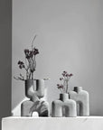 Three 101Cph Cobra Tall Mini Dark Grey 211034 vases sitting on a table in front of a white wall.