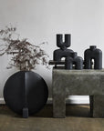 A group of 101Cph Cobra Double Mini Black 203025 vases on a table next to a plant, from the brand 101 Copenhagen.