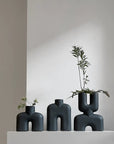 Three 101Cph Cobra Uno Mini Black 203024 vases with plants on top of them.