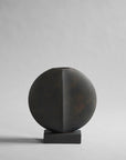 A black vase on a grey background showcasing the 101Cph Guggenheim Mini Coffee 111220 from the 101 Copenhagen Arts Movement.