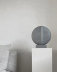 A 101Cph Guggenheim Mini Dark Grey 203005, reminiscent of the Cobra Arts Movement, sitting on a pedestal in a living room. (Brand Name: 101 Copenhagen)