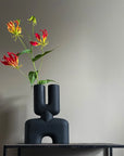 A 101Cph Cobra Double Medio Black 212006 vase with flowers sitting on a table.