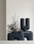 Two black 101Cph Cobra Double Medio Black 212006 vases sitting on top of a white shelf.