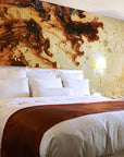 A bed in a hotel room with Alex Turco Liquid Dreams Orange Souls, a decorative mural on the wall showcasing interior design art panels.