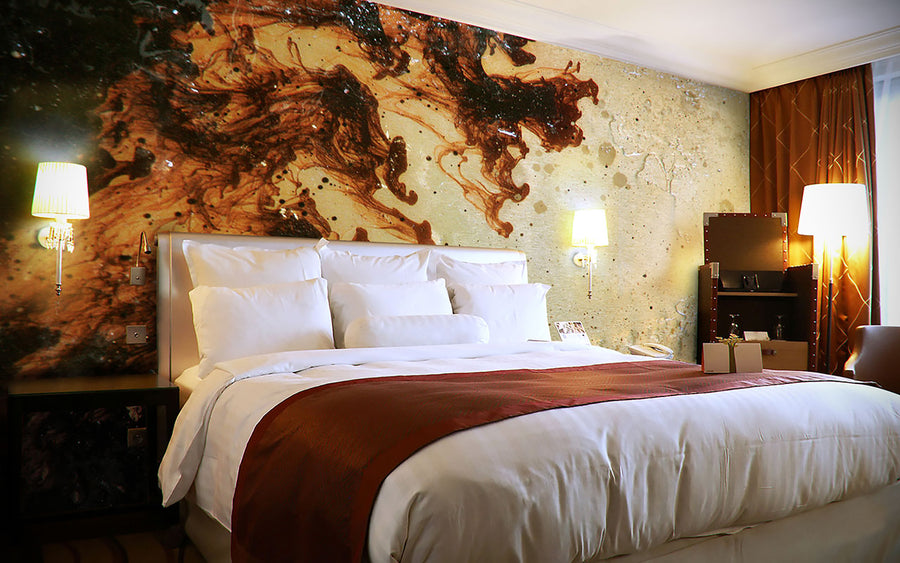 A bed in a hotel room with Alex Turco Liquid Dreams Orange Souls, a decorative mural on the wall showcasing interior design art panels.