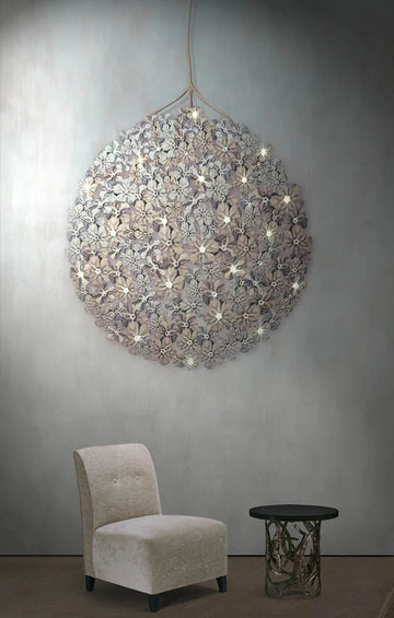 A Germanium LED Wall Paper with Swarovski chandelier hanging above a chair in a room, providing ambient lighting. (Brand: Meystyle)